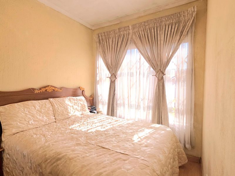 A compact bedroom featuring neutral wall finishes and natural light through window treatments.