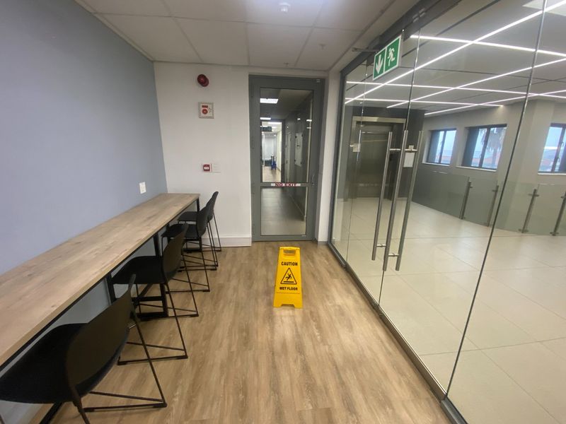 Modern commercial hallway featuring a built-in desk area, glass partition walls, and professional lighting, providing a clean and functional transition space.