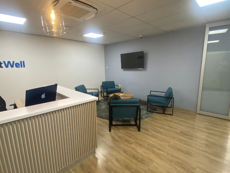Modern commercial reception area featuring a custom reception desk, wood-look laminate flooring, and a professional waiting area with integrated ceiling lighting.