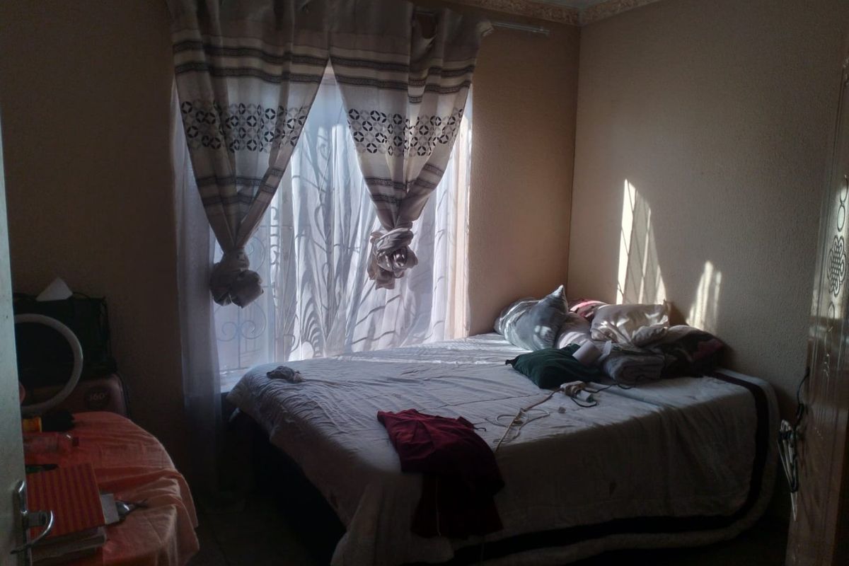 A bedroom featuring a window with security bars and decorative ceiling cornicing, providing a functional space with natural light.