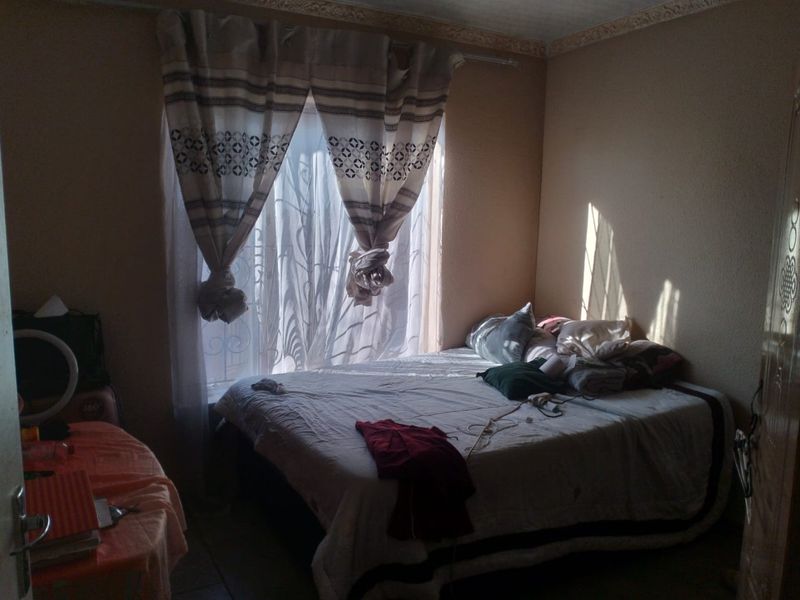 A bedroom featuring a window with security bars and decorative ceiling cornicing, providing a functional space with natural light.