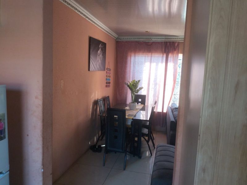 A dining area featuring tiled flooring and decorative ceiling cornicing, requiring cosmetic updates to the wall finishes to improve the overall aesthetic.