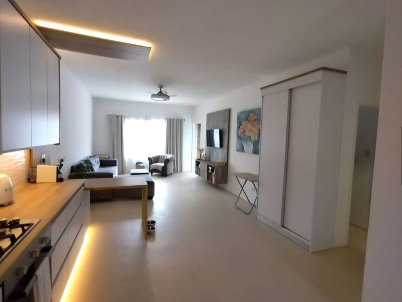 Modern open-plan living area featuring a sleek kitchen with under-cabinet lighting, integrated gas hob, and a spacious built-in wardrobe for storage.