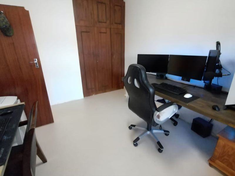 A bedroom featuring built-in wooden wardrobes and a functional workspace area.
