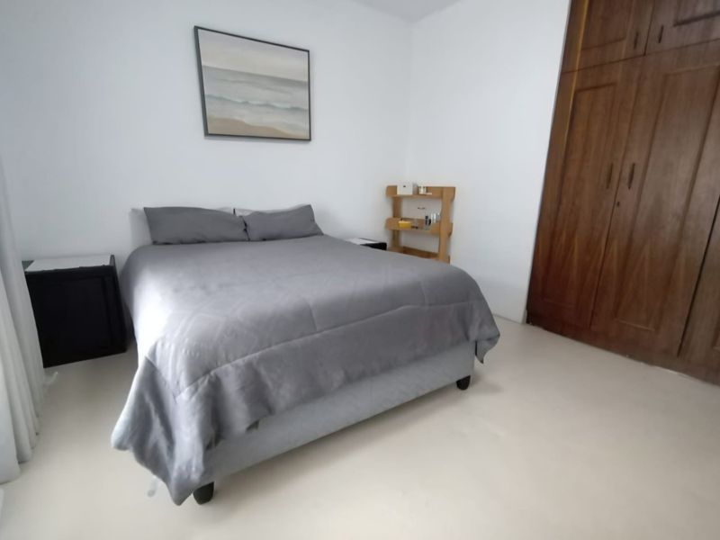 A bedroom featuring neutral walls, tiled flooring, and a large built-in wooden wardrobe providing ample storage space.