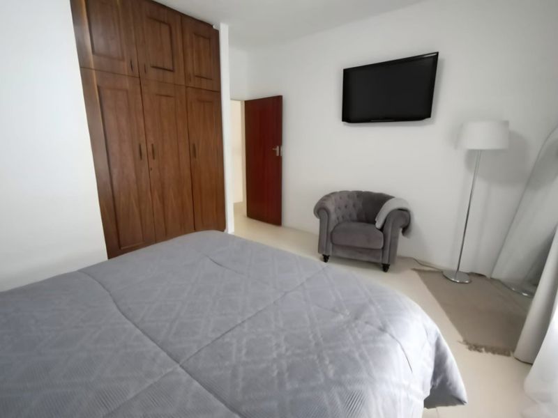 A well-maintained bedroom featuring built-in wooden wardrobes and neutral tiled flooring, providing a clean and functional living space.
