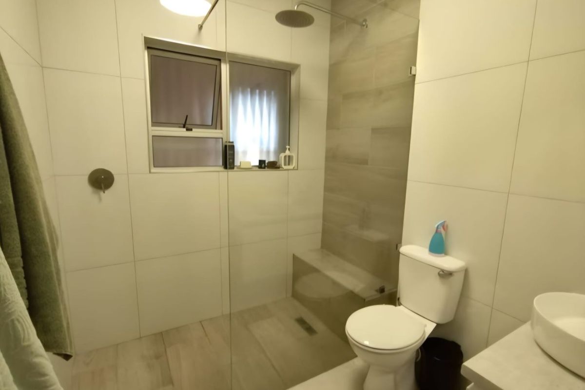 Modern bathroom featuring a walk-in shower with a glass screen, rain shower head, built-in bench, and a contemporary vessel sink.