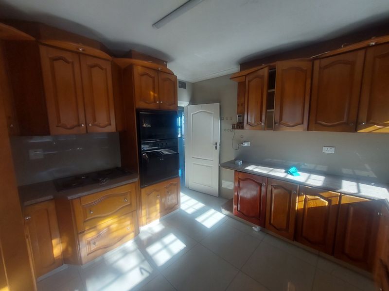 A functional kitchen featuring traditional wooden cabinetry, built-in oven, hob, and tiled flooring, offering a classic layout ready for modern updates.