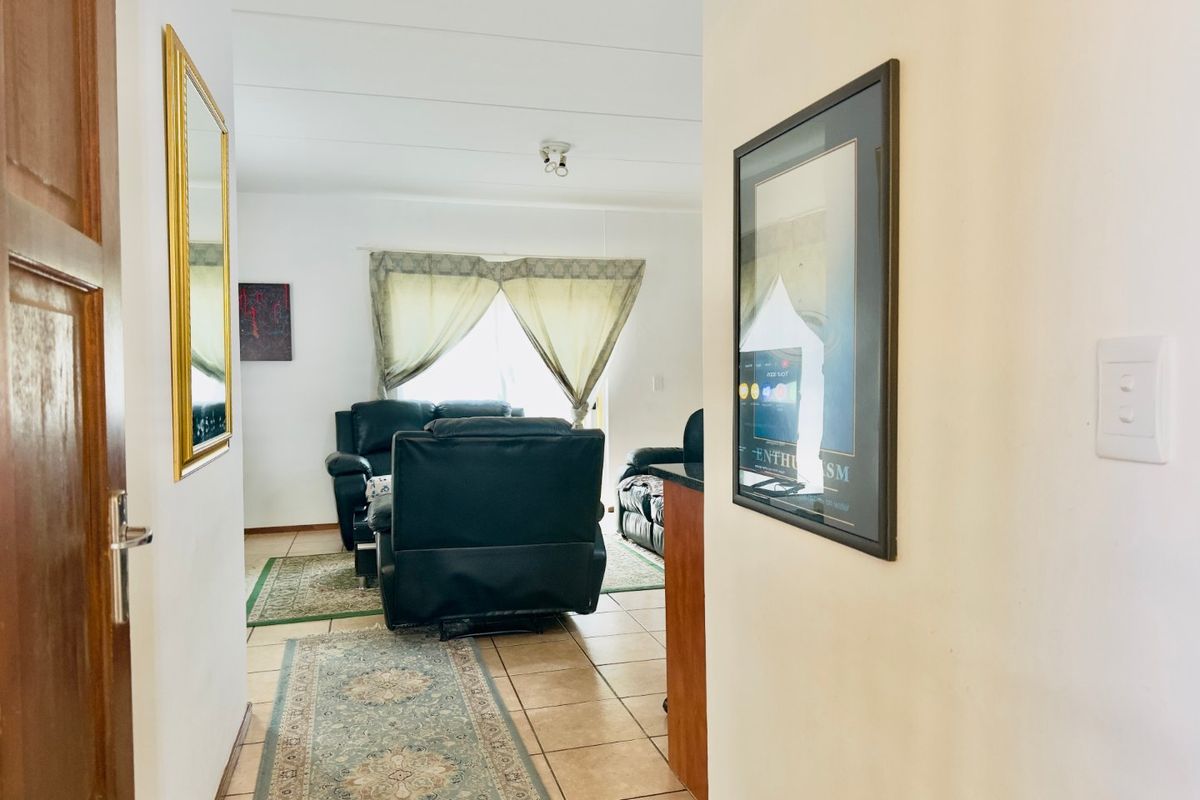 A view from the hallway into the living area, featuring tiled flooring and neutral wall finishes.