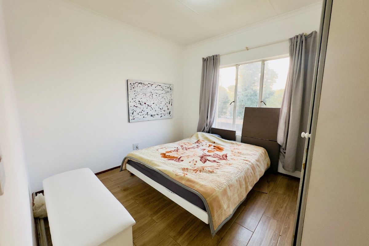 A functional bedroom featuring wood-look tile flooring and a built-in wardrobe, offering a neutral canvas for personalization.
