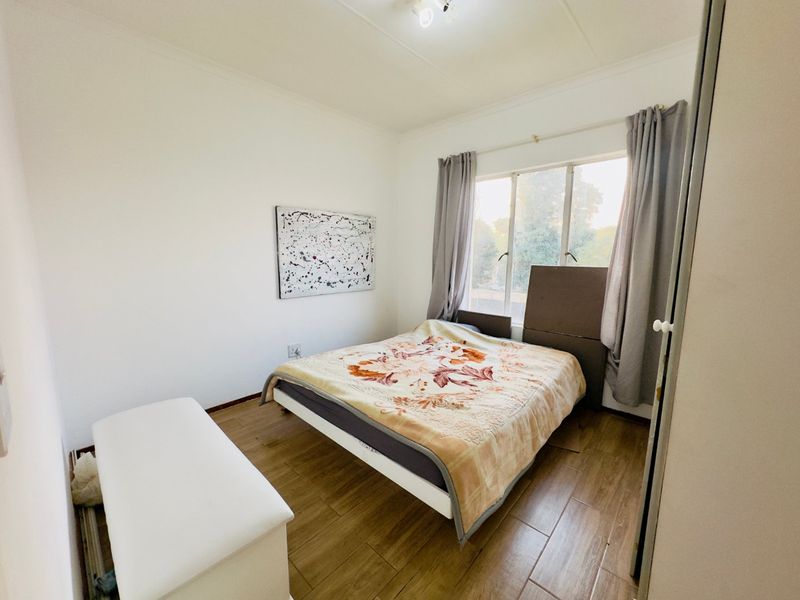 A functional bedroom featuring wood-look tile flooring and a built-in wardrobe, offering a neutral canvas for personalization.