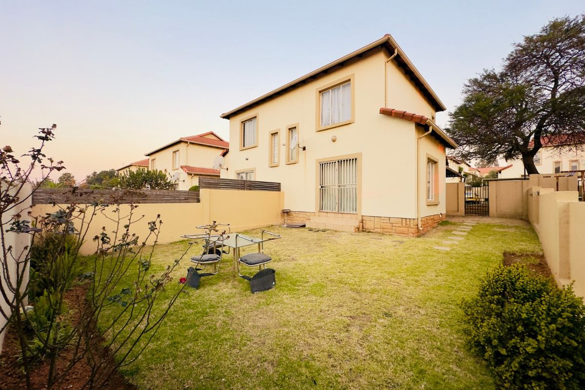 Rear view of the apartment featuring a private garden, stone-clad base, and sliding door access with security bars.