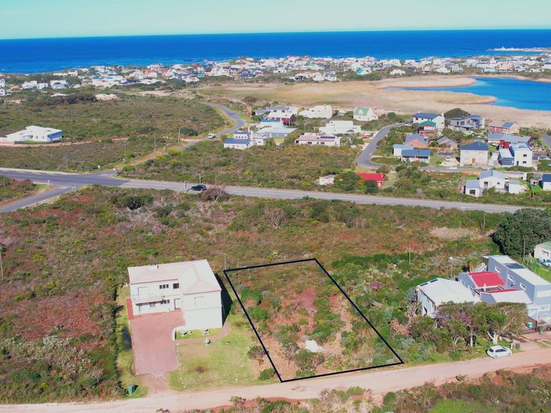 Aerial view of a vacant residential plot situated in a coastal neighborhood, highlighting the property boundaries and surrounding landscape.