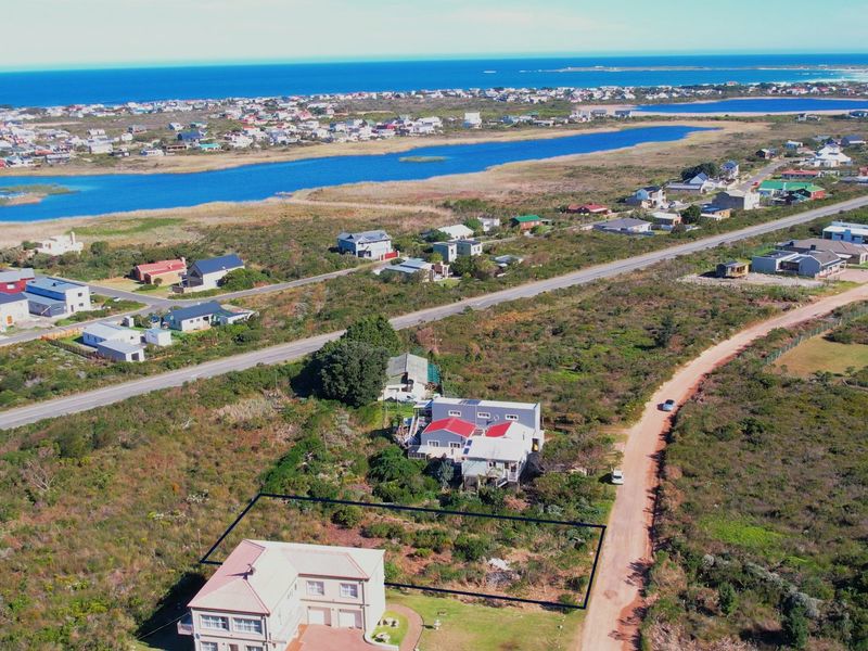 Aerial view of a residential vacant land plot situated in a coastal area with surrounding neighborhood and landscape views.