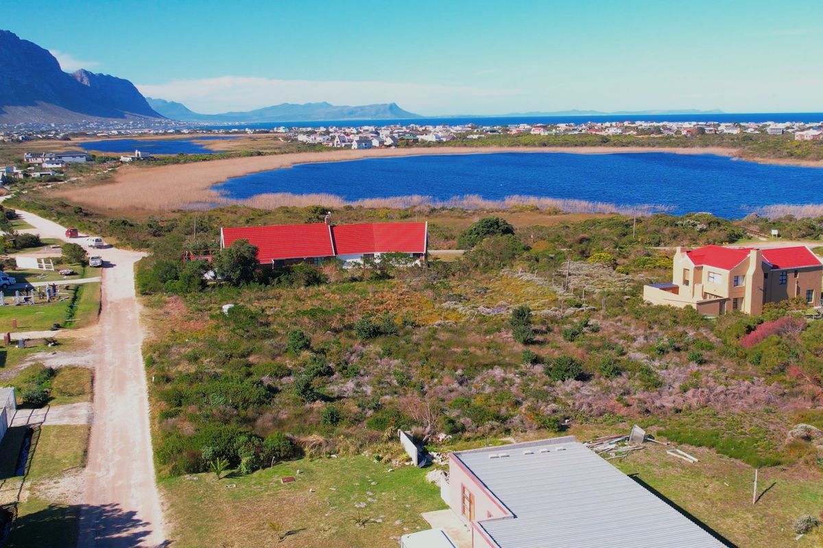 Aerial view of a vacant residential plot featuring natural coastal vegetation, adjacent to a lake and established residential properties.
