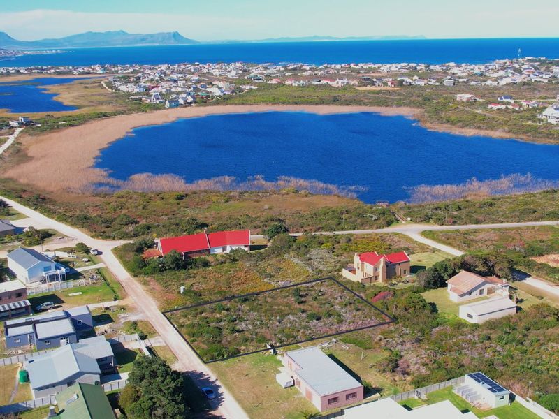Aerial view of a vacant residential plot situated in a coastal area with scenic lake and mountain views.