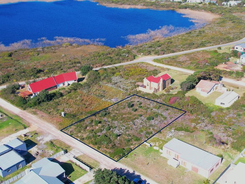 Aerial view of a vacant residential plot situated in a coastal area, highlighting the property boundaries and surrounding landscape.