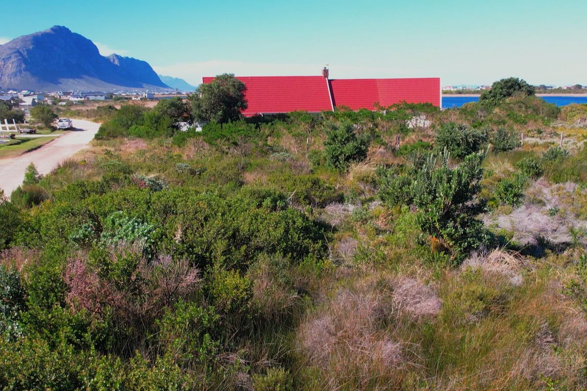 An aerial view of a vacant residential plot featuring natural vegetation, with a distant view of the coastline and surrounding landscape.
