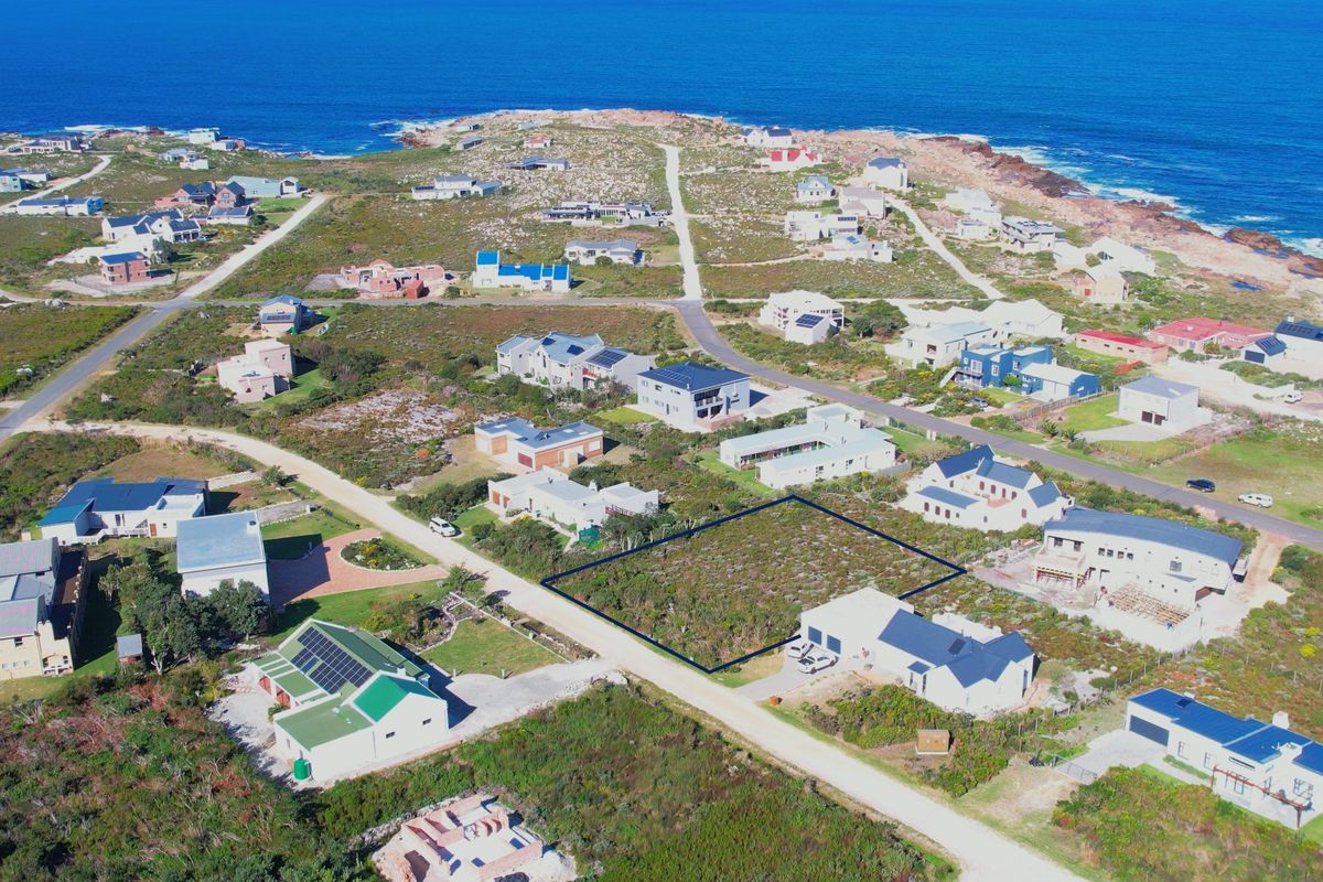 An aerial view of a vacant residential plot situated in a coastal neighborhood, highlighting the property boundaries and surrounding landscape.