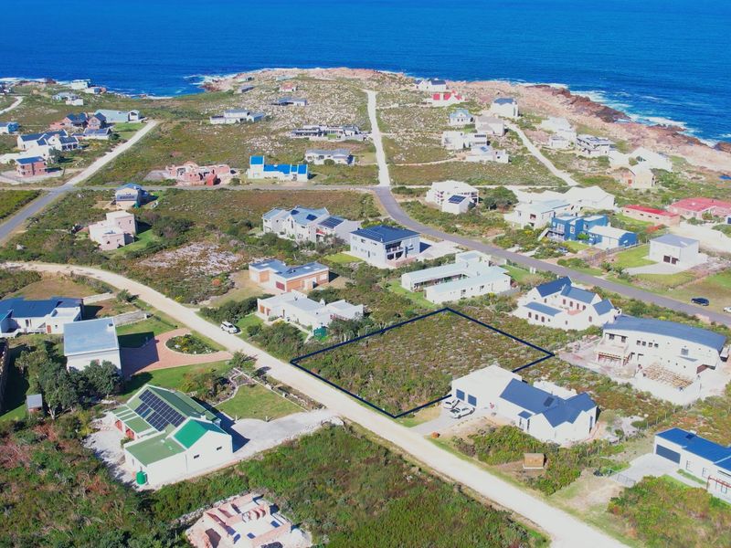 An aerial view of a vacant residential plot situated in a coastal neighborhood, highlighting the property boundaries and surrounding landscape.