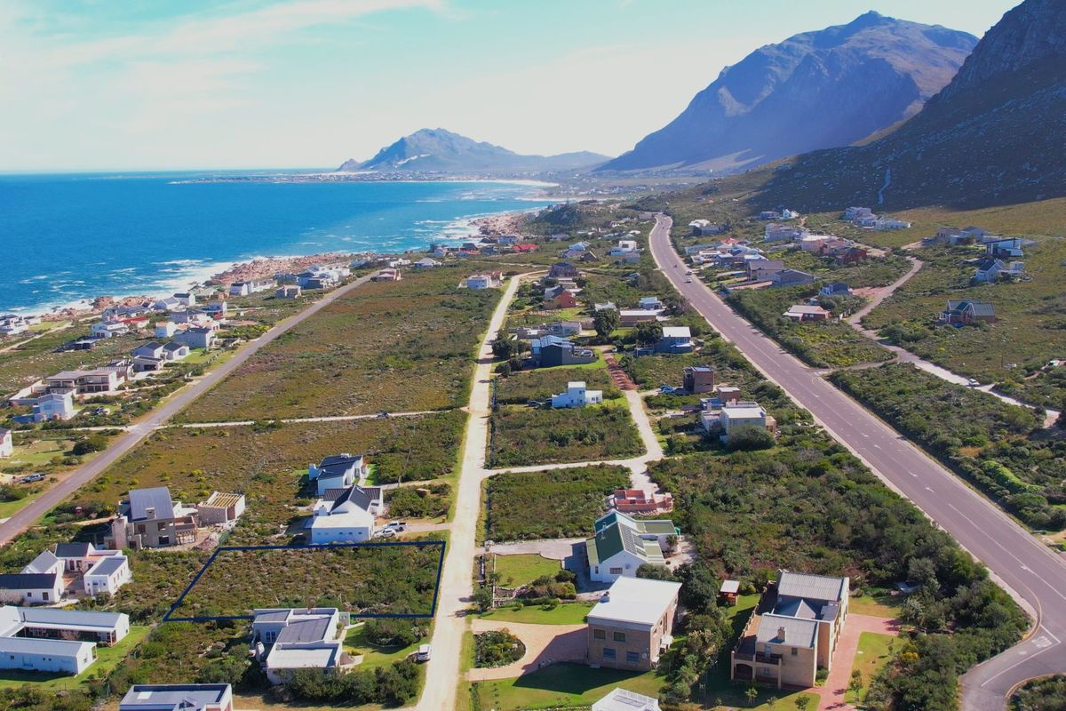 Aerial view of a vacant residential plot situated in a coastal neighborhood with mountain and ocean views.