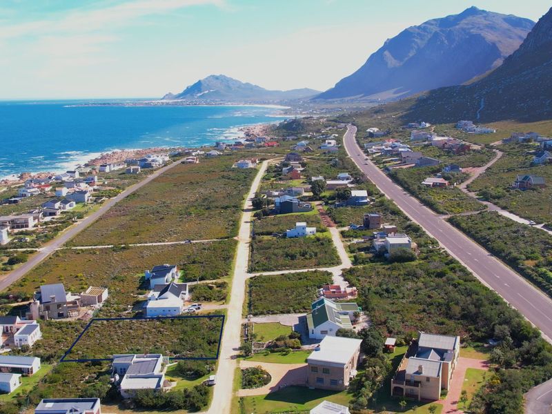 Aerial view of a vacant residential plot situated in a coastal neighborhood with mountain and ocean views.