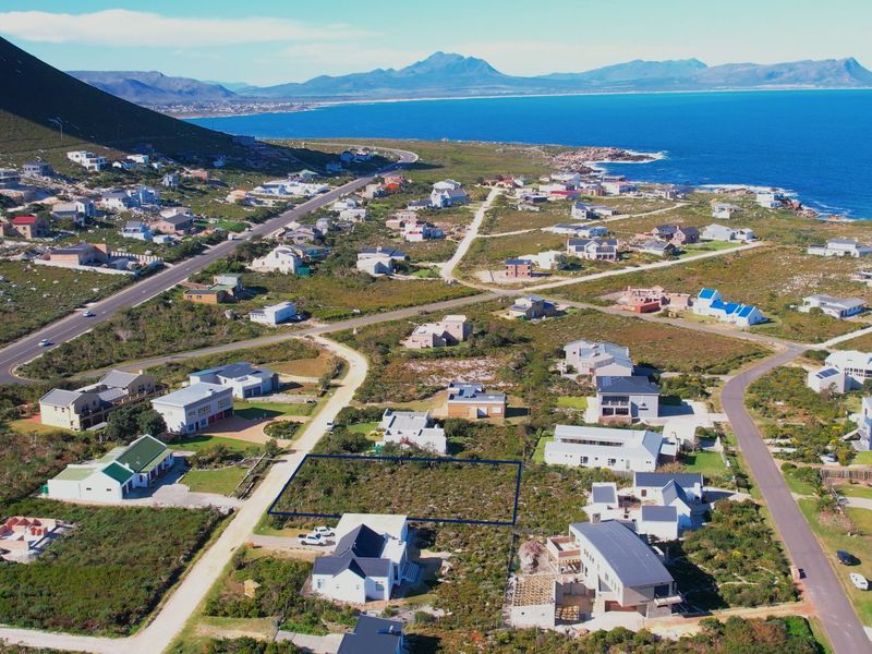 Aerial view of a vacant residential plot situated in a coastal neighborhood with mountain and ocean views.