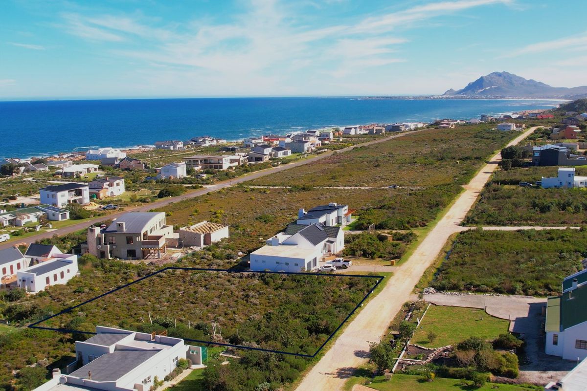 Aerial view of a vacant residential plot situated in a coastal estate, featuring natural vegetation and proximity to the ocean.