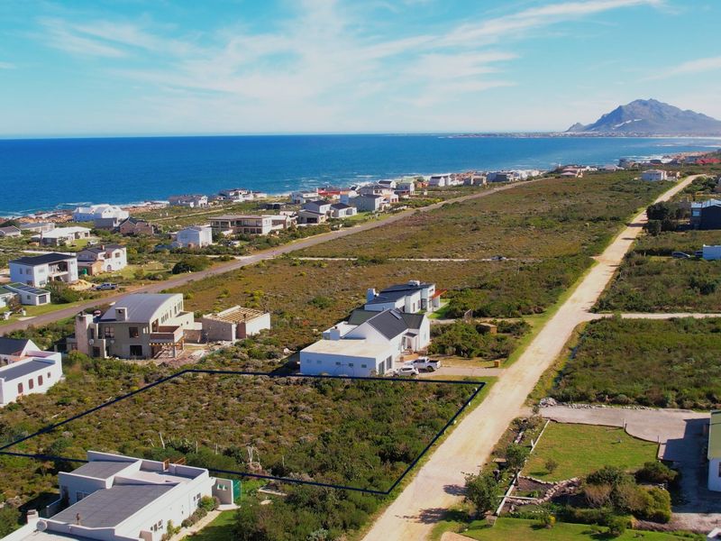 Aerial view of a vacant residential plot situated in a coastal estate, featuring natural vegetation and proximity to the ocean.