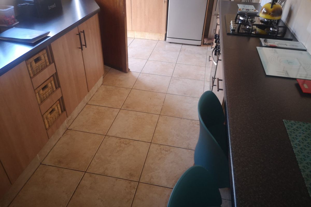 A functional kitchen featuring laminate cabinetry, dark countertops, a gas hob, and tiled flooring, offering a practical layout for daily meal preparation.