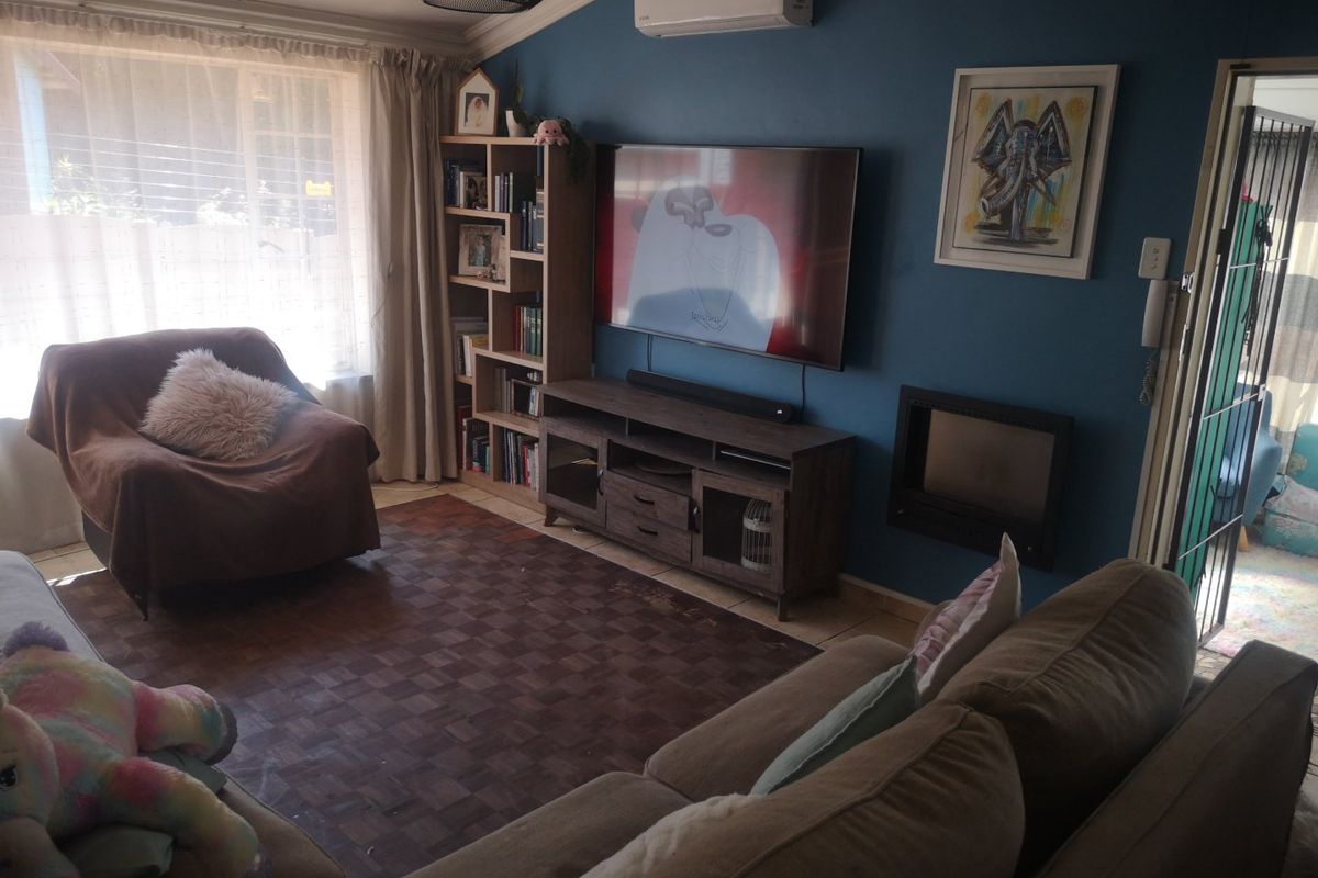A cozy living room featuring parquet flooring, a built-in fireplace, and a wall-mounted air conditioning unit, offering a comfortable and functional space.