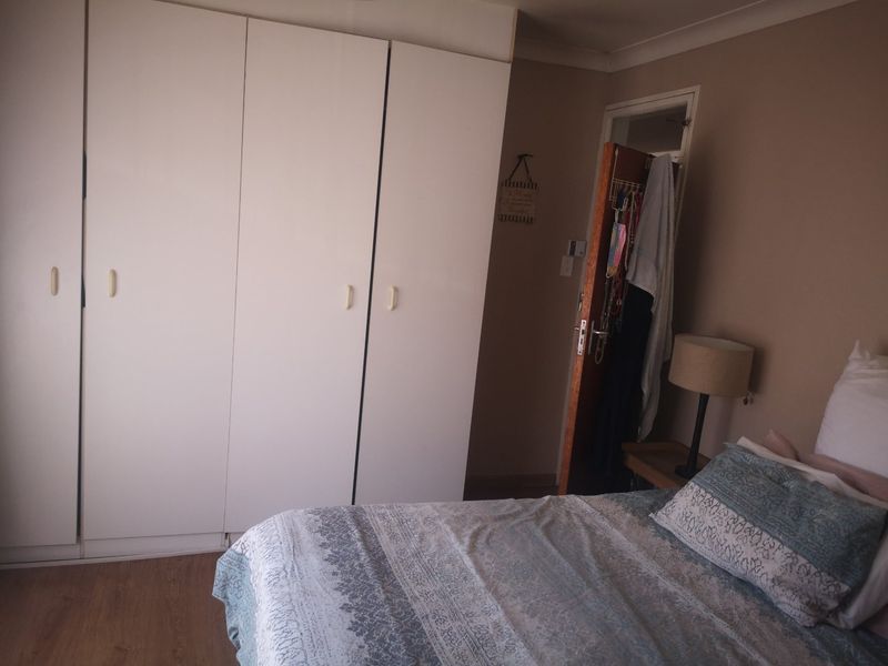 A bedroom featuring built-in cupboards and laminate flooring, offering a functional space with neutral wall tones.