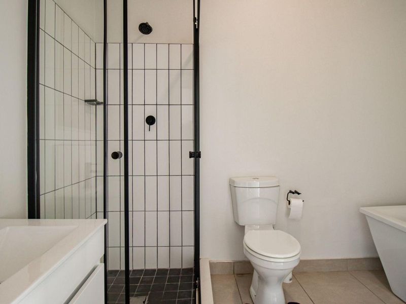 Modern bathroom featuring a walk-in shower with black-framed glass, a freestanding bathtub, and a vanity basin.