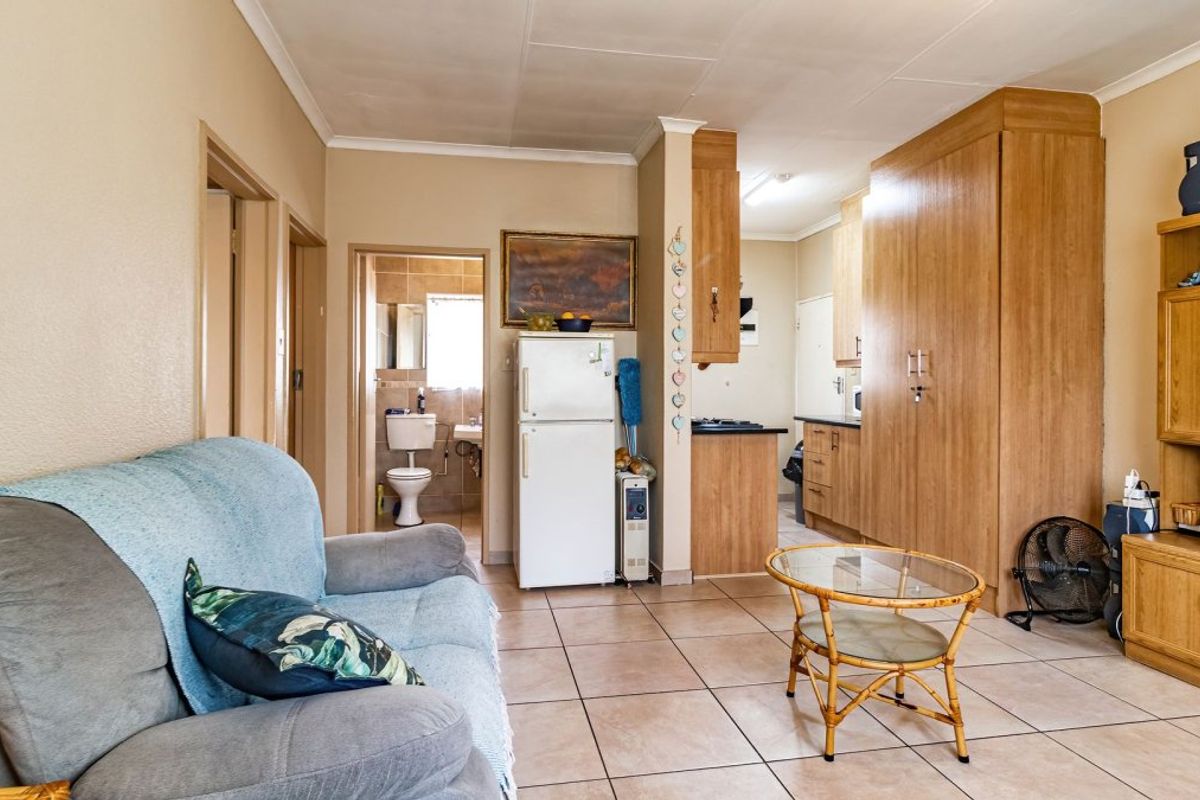 Open plan living area featuring tiled flooring, built-in kitchen cabinetry, and integrated storage, with direct access to an adjacent bathroom.