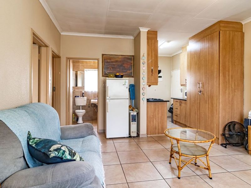 Open plan living area featuring tiled flooring, built-in kitchen cabinetry, and integrated storage, with direct access to an adjacent bathroom.