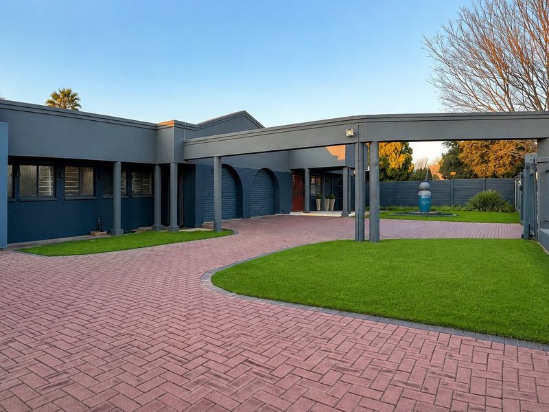 A well-maintained front exterior featuring a paved driveway, covered walkway, and manicured lawn with modern dark-toned architectural finishes.