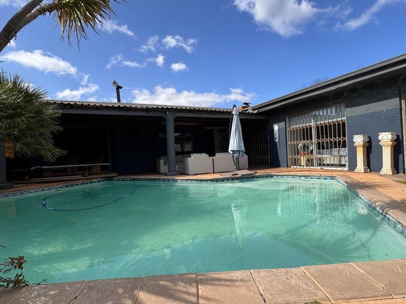 Outdoor pool area featuring a swimming pool, covered patio space, and security gates, providing a functional area for outdoor relaxation and entertainment.