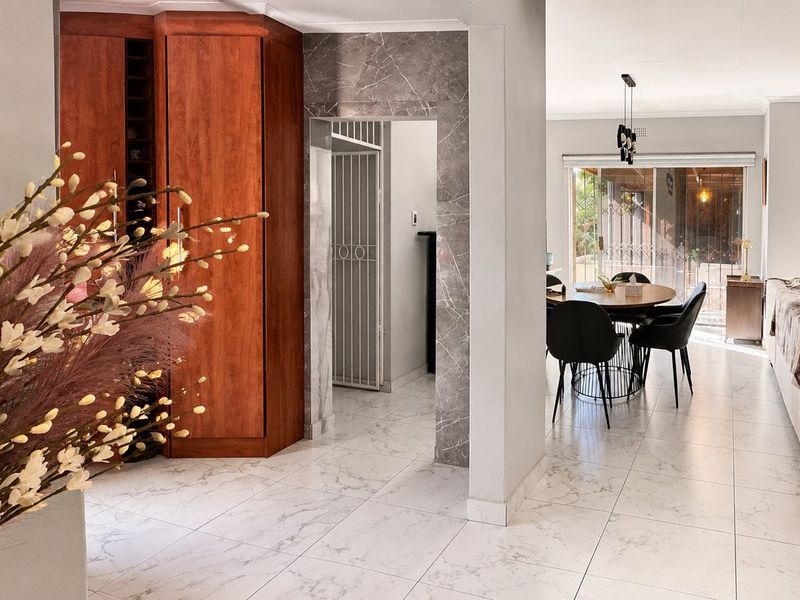 Open-plan living and dining area featuring marble-look floor tiles, built-in cabinetry, and seamless flow to the outdoor patio through sliding glass doors.