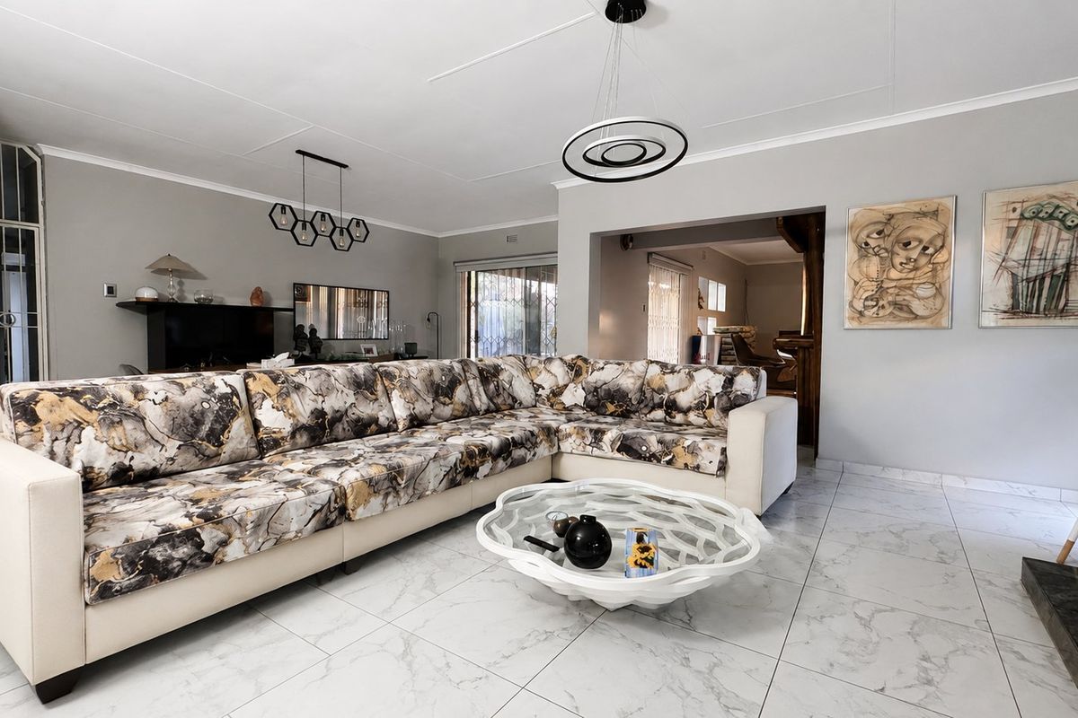 Spacious living room featuring modern marble-look floor tiles, contemporary pendant lighting, and neutral wall finishes, creating a bright and open atmosphere.