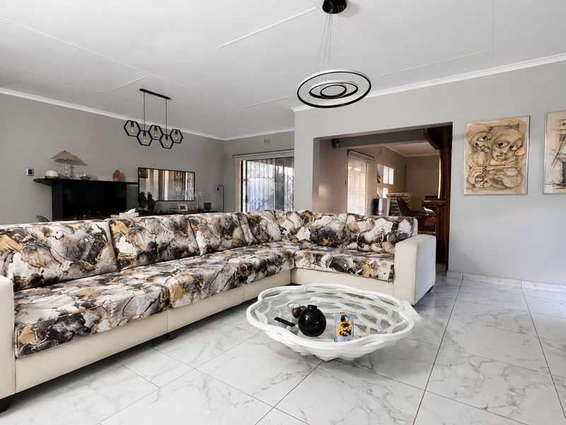 Spacious living room featuring modern marble-look floor tiles, contemporary pendant lighting, and neutral wall finishes, creating a bright and open atmosphere.