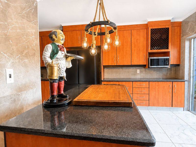 A well-maintained kitchen featuring warm wooden cabinetry, granite countertops, a built-in microwave, and direct access to an outdoor area through sliding glass doors.