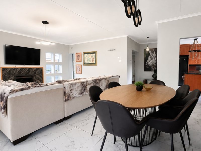 Spacious open-plan living and dining area featuring marble-look floor tiles, a modern built-in fireplace, and a seamless transition to the kitchen.