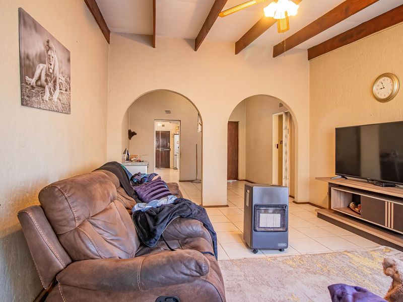 Spacious living room featuring exposed timber ceiling beams, tiled flooring, and distinctive arched doorways leading to adjacent areas of the home.