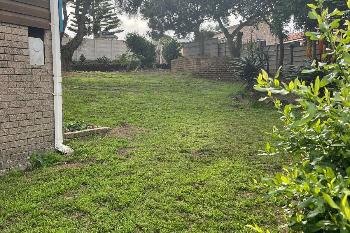 A spacious rear garden featuring a lawn area, brick boundary walls, and established trees, providing a private outdoor space.