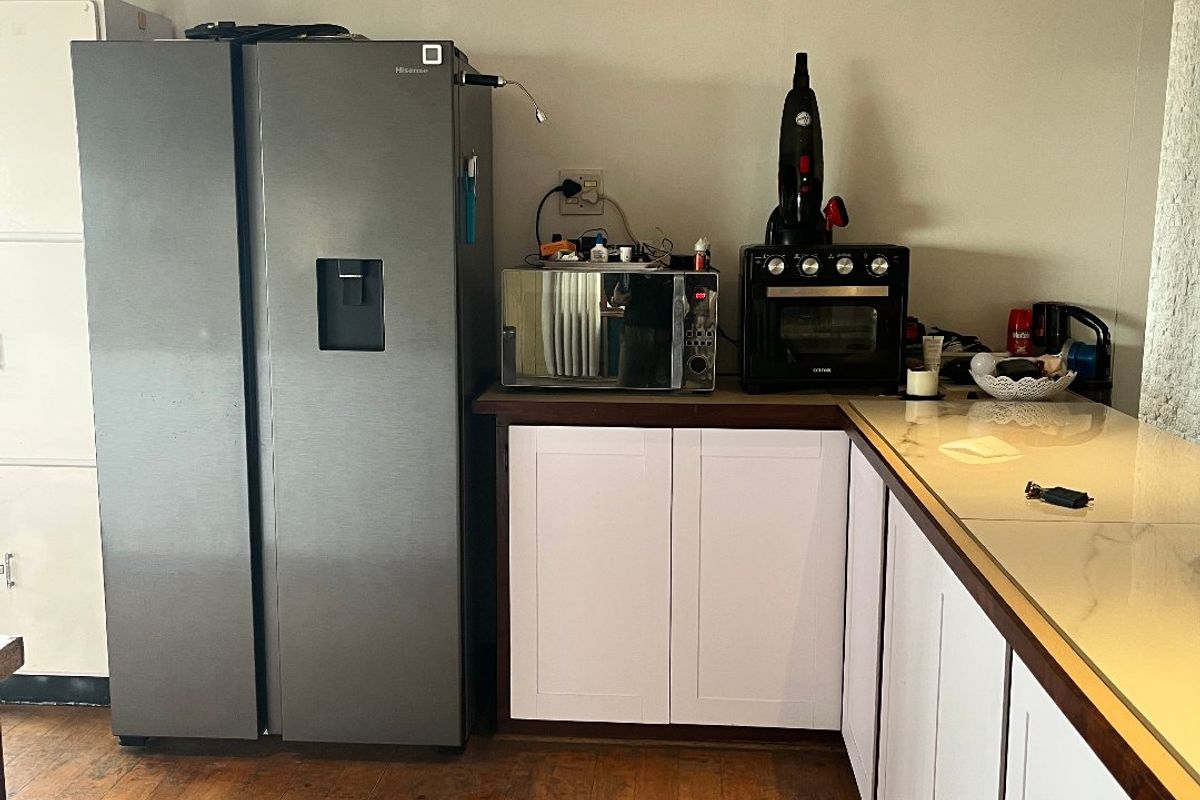 A functional kitchen area featuring white cabinetry, stone-look countertops, and warm timber flooring, providing a practical workspace with integrated storage.