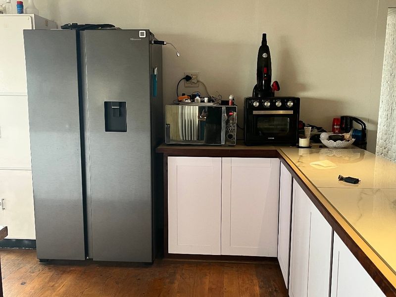 A functional kitchen area featuring white cabinetry, stone-look countertops, and warm timber flooring, providing a practical workspace with integrated storage.