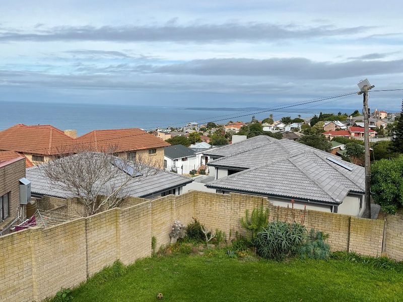 Elevated view overlooking a residential neighborhood with a coastal outlook and a private backyard with a brick boundary wall.