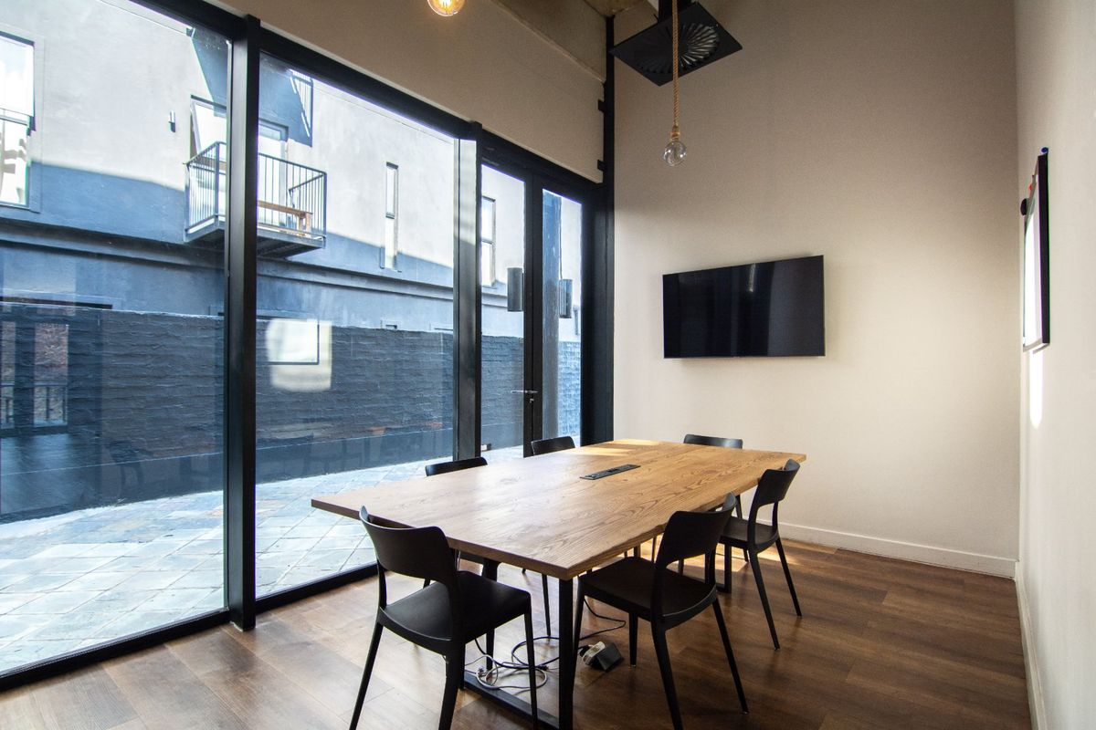 Modern living area featuring floor-to-ceiling windows with black metal frames, hardwood flooring, and an exposed ceiling design.