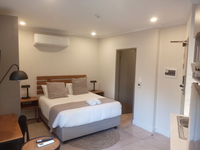 A well-maintained bedroom featuring tiled flooring, recessed downlighting, and a wall-mounted split-system air conditioner.