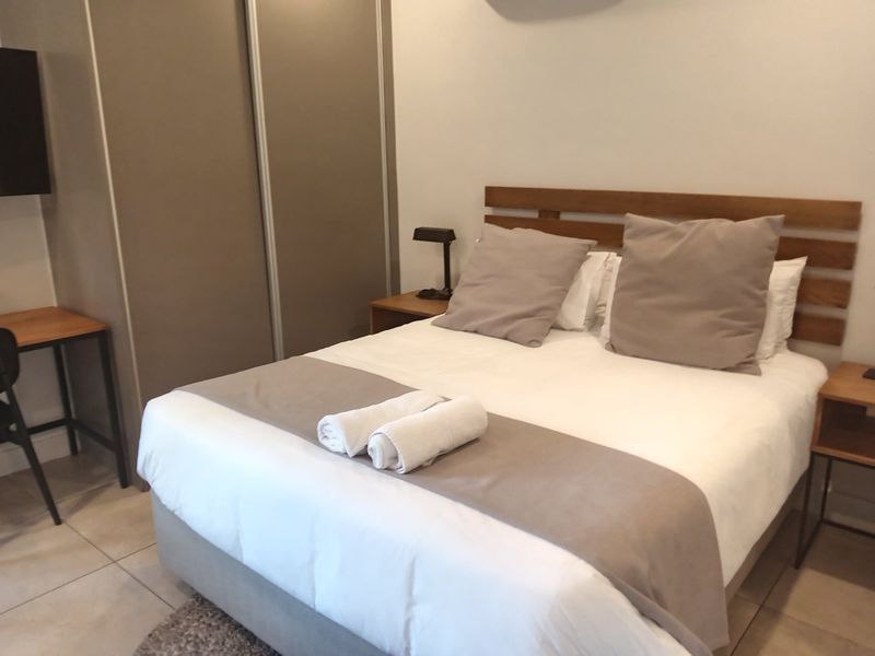 A well-maintained bedroom featuring tiled flooring, a built-in wardrobe, and an integrated air conditioning unit.